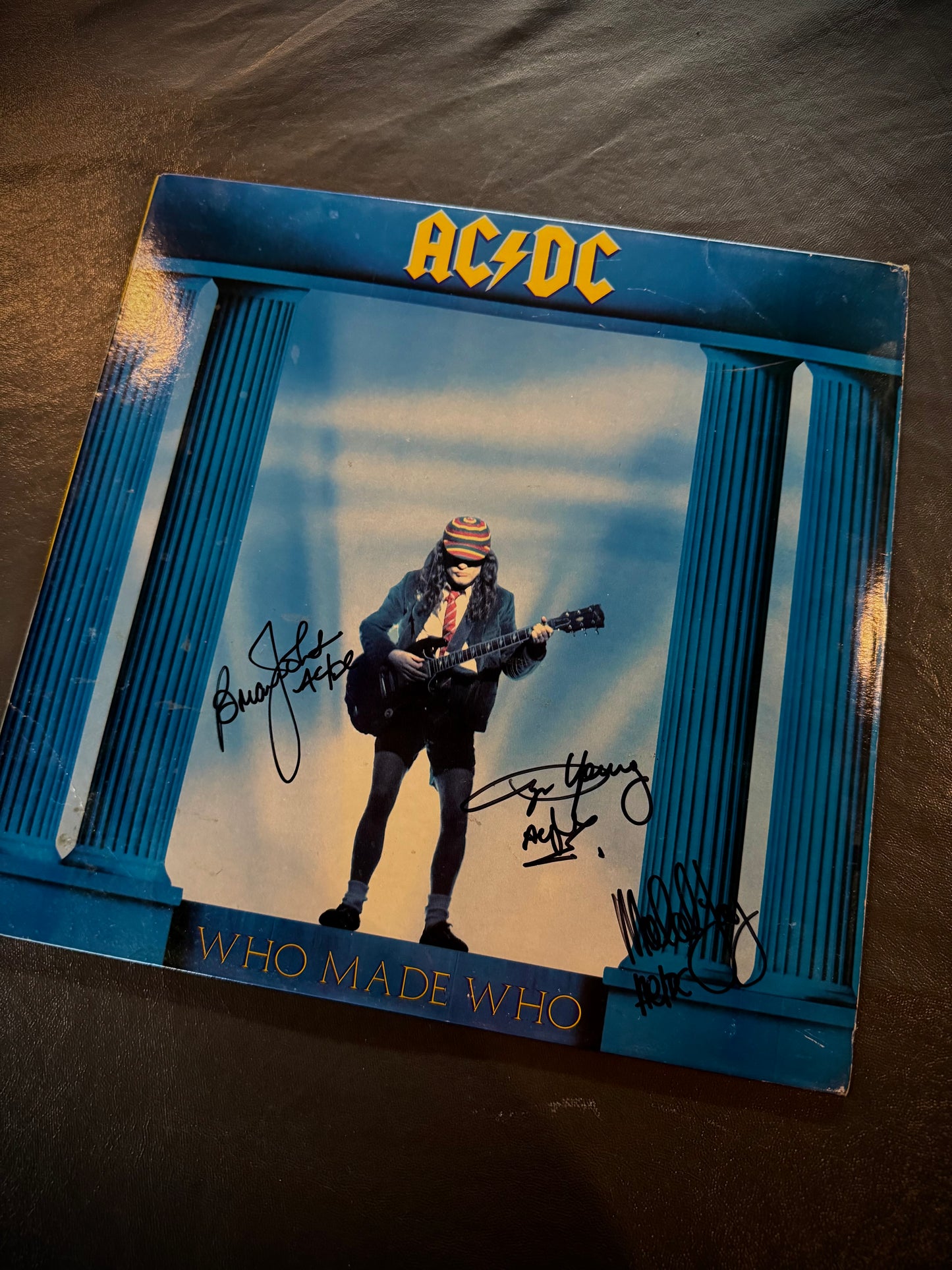 AC/DC album cover with a person playing guitar, signed by band members.