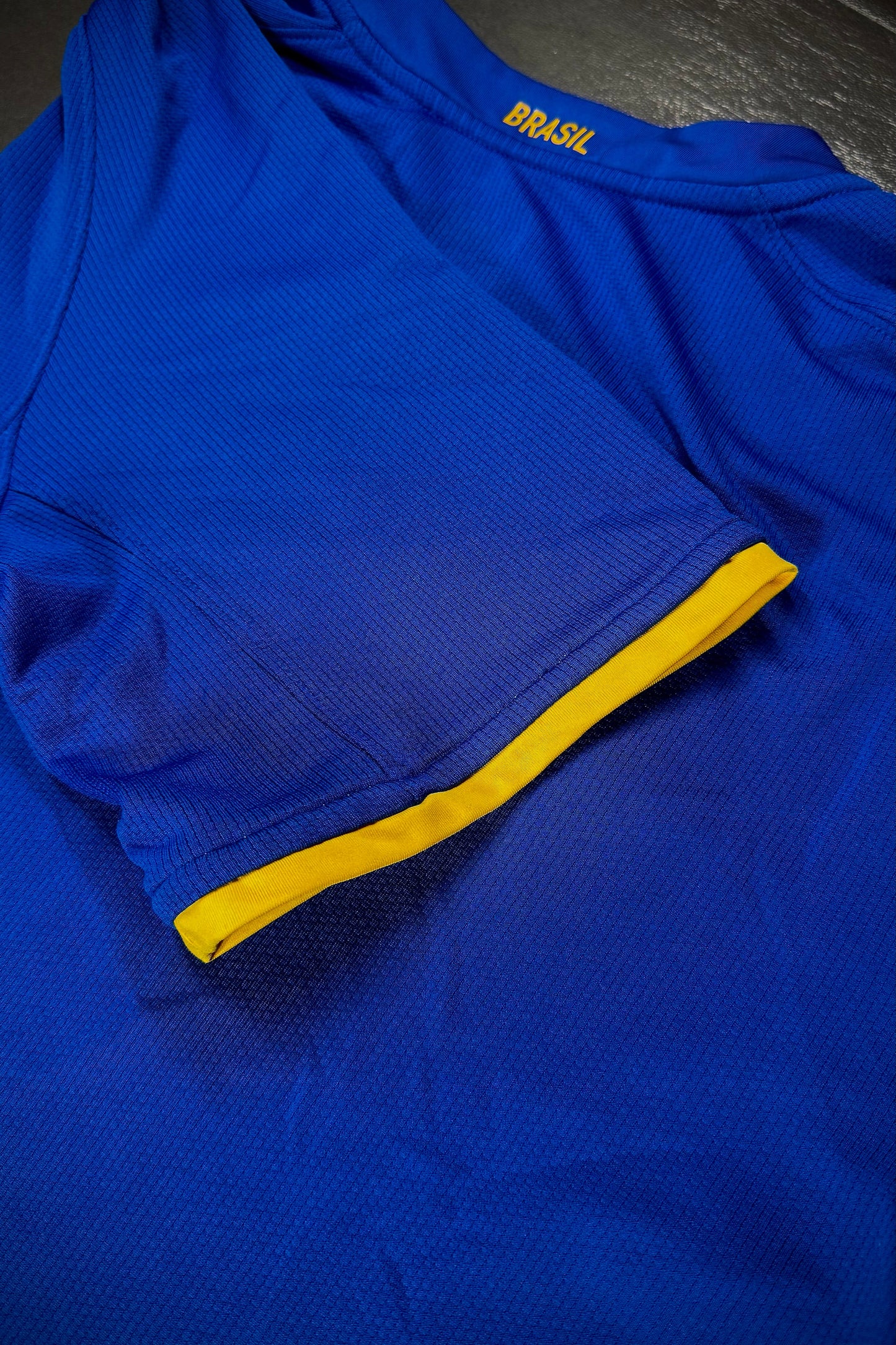 Blue athletic shirt with yellow accents on a dark surface