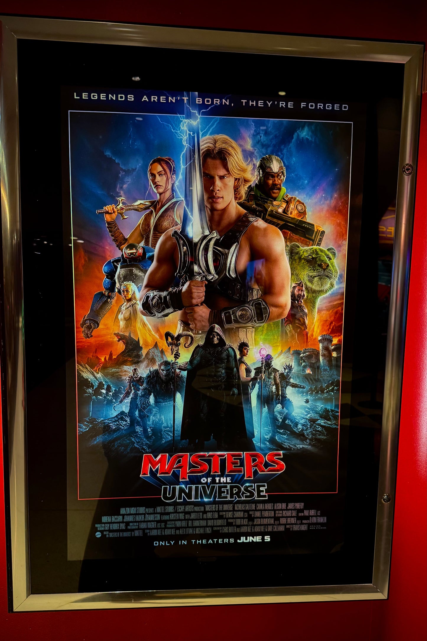 Framed movie poster for 'Masters of the Universe' on a red wall.