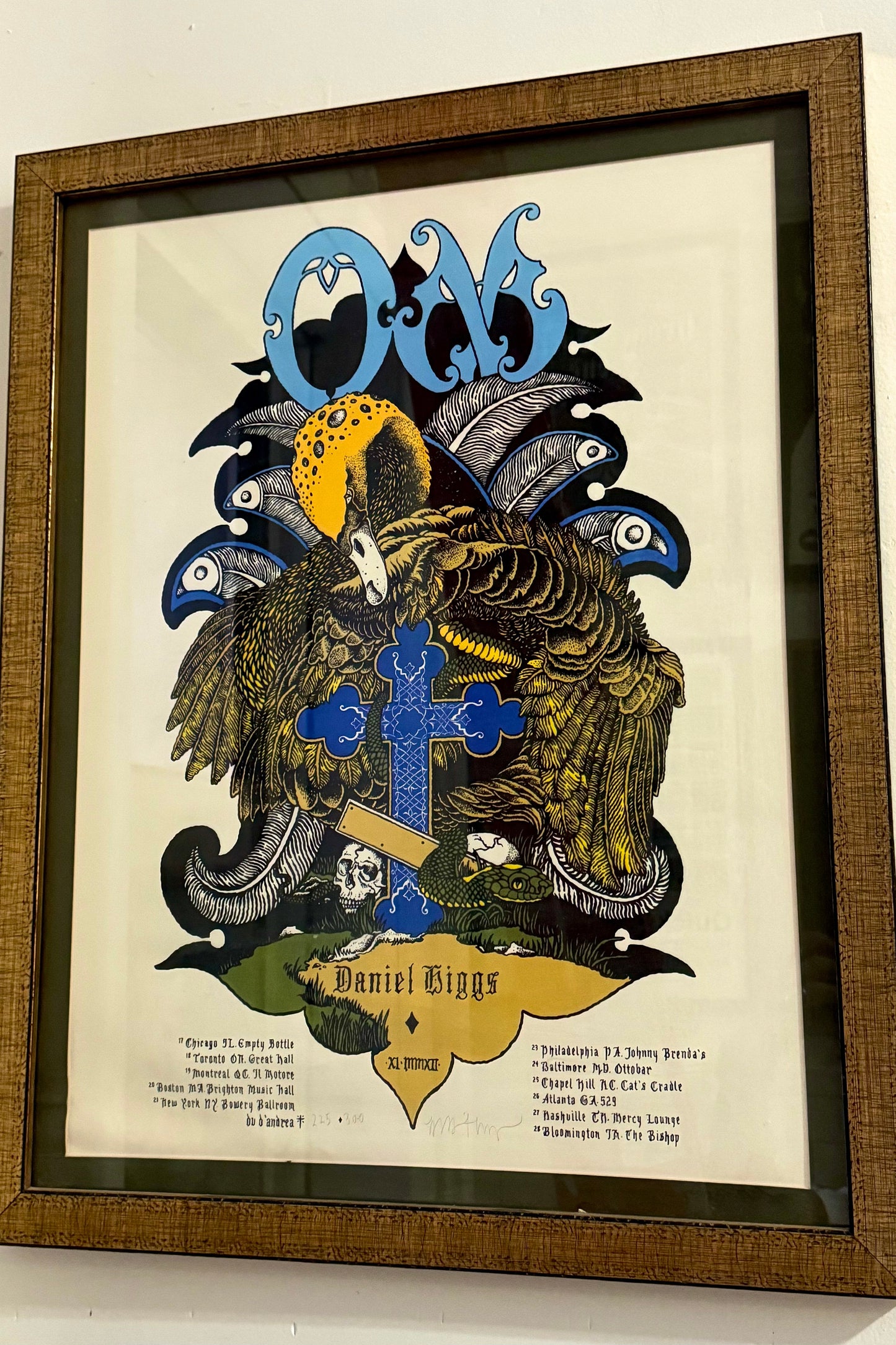 Framed screen print poster featuring the band 'OM' with a distinctive graphic design in multiple colors, signed and numbered edition of 300.