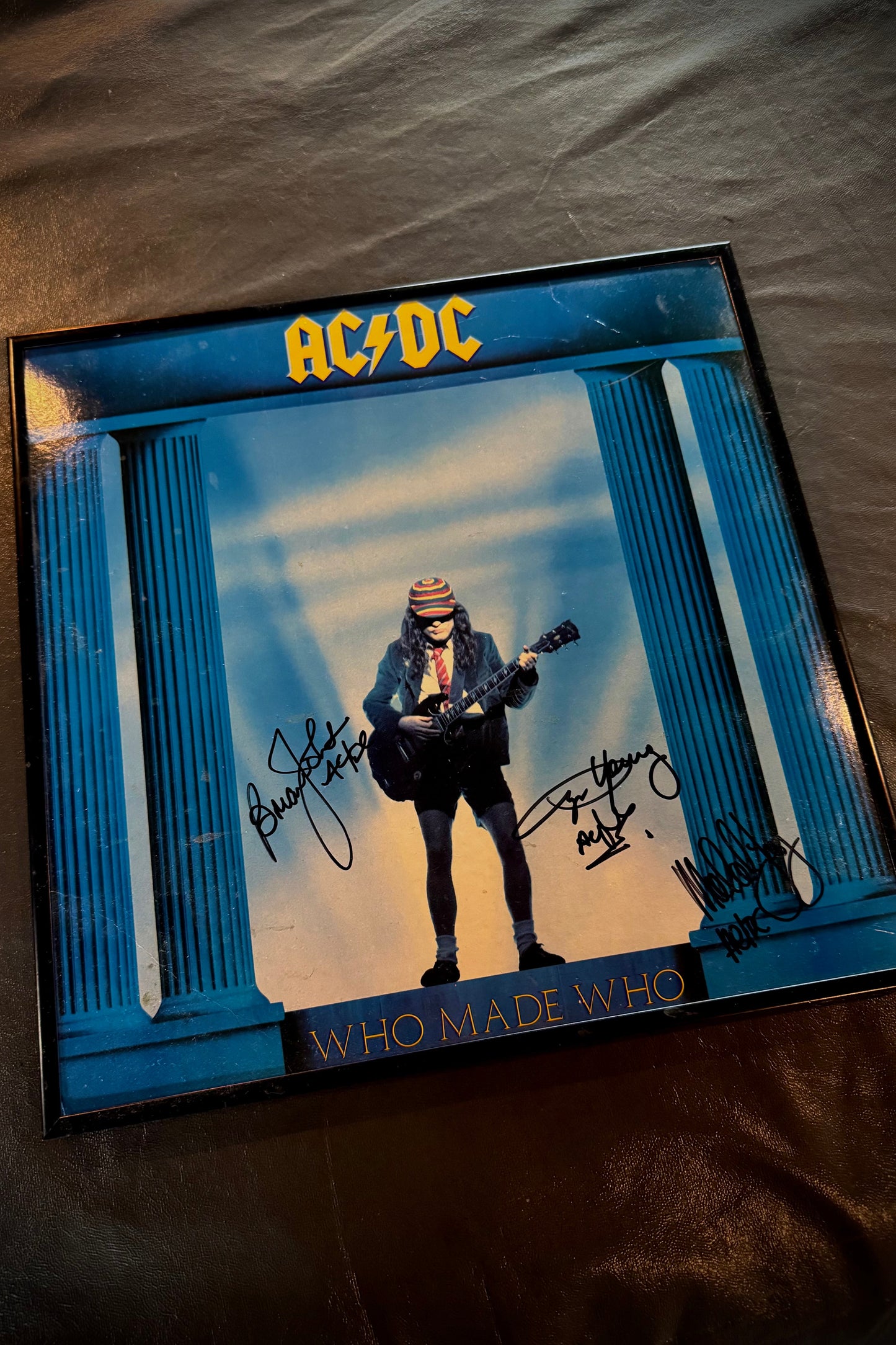AC/DC album cover with a guitar player and signature on a textured surface