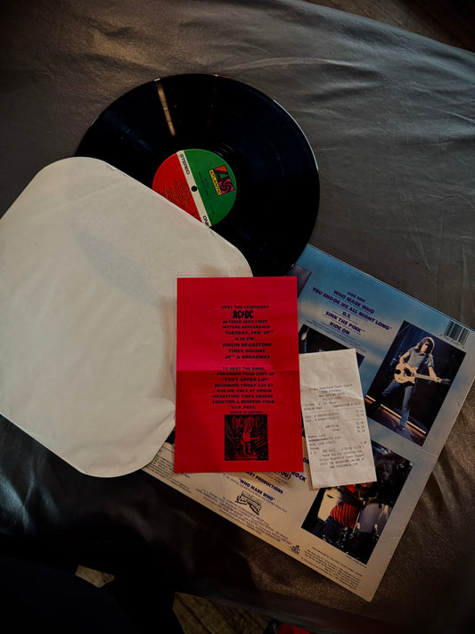 Vinyl record with a red inner sleeve and promotional material on a bed