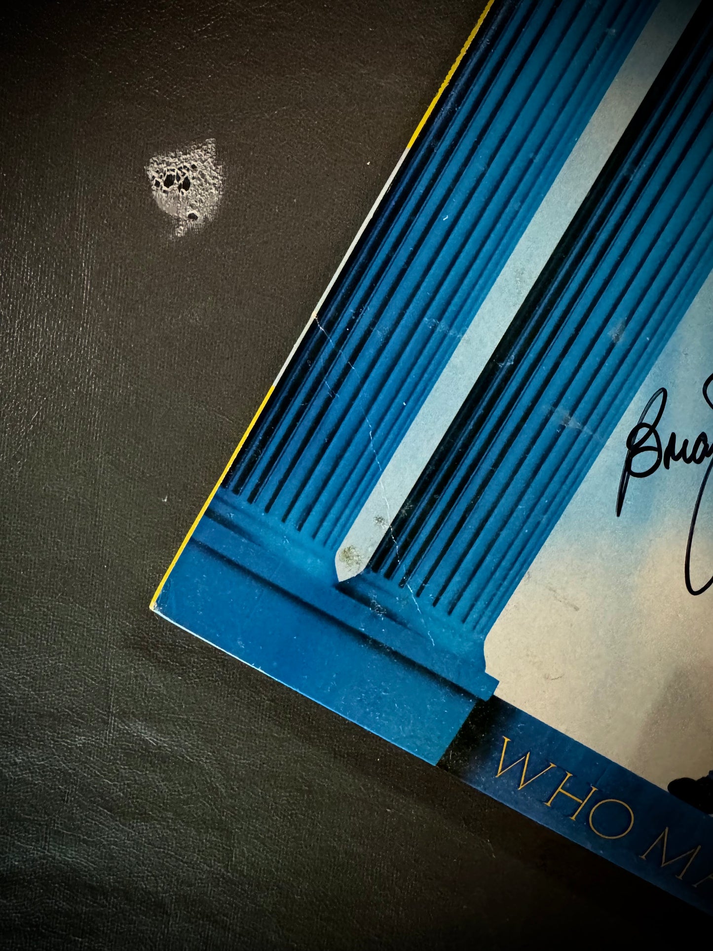 Close-up of a blue book with a signature on a dark surface
