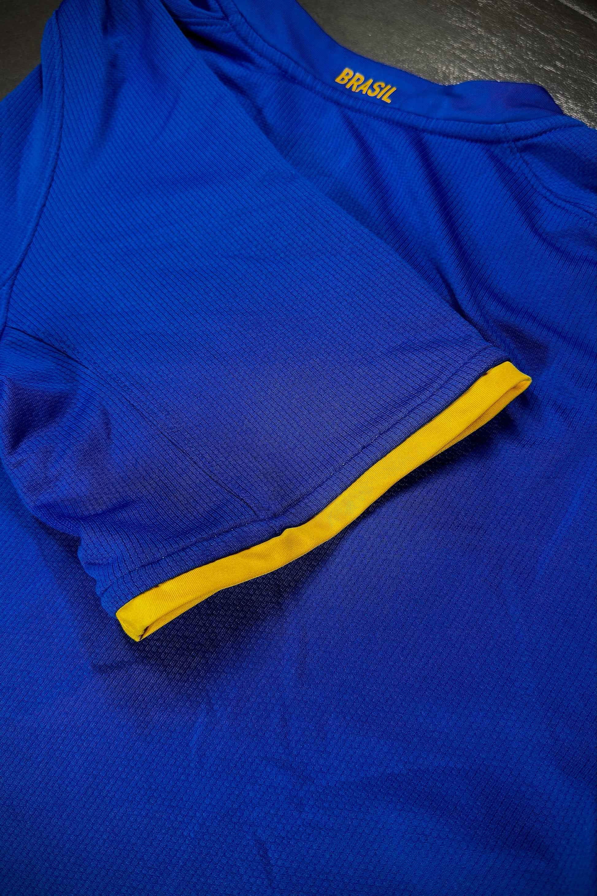 Blue athletic shirt with yellow accents on a dark surface