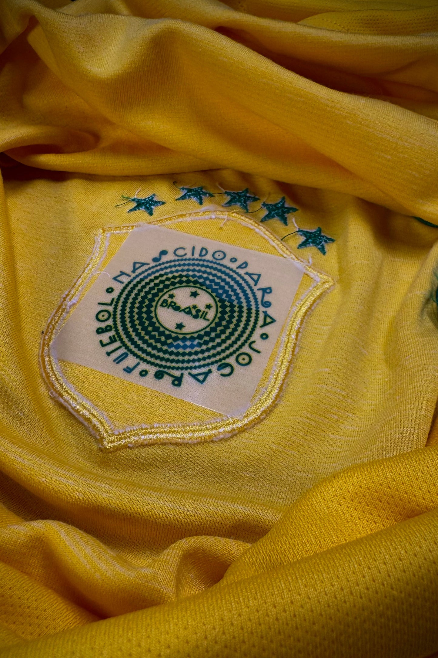 Close-up of a yellow sports jersey with a logo and text on the chest.