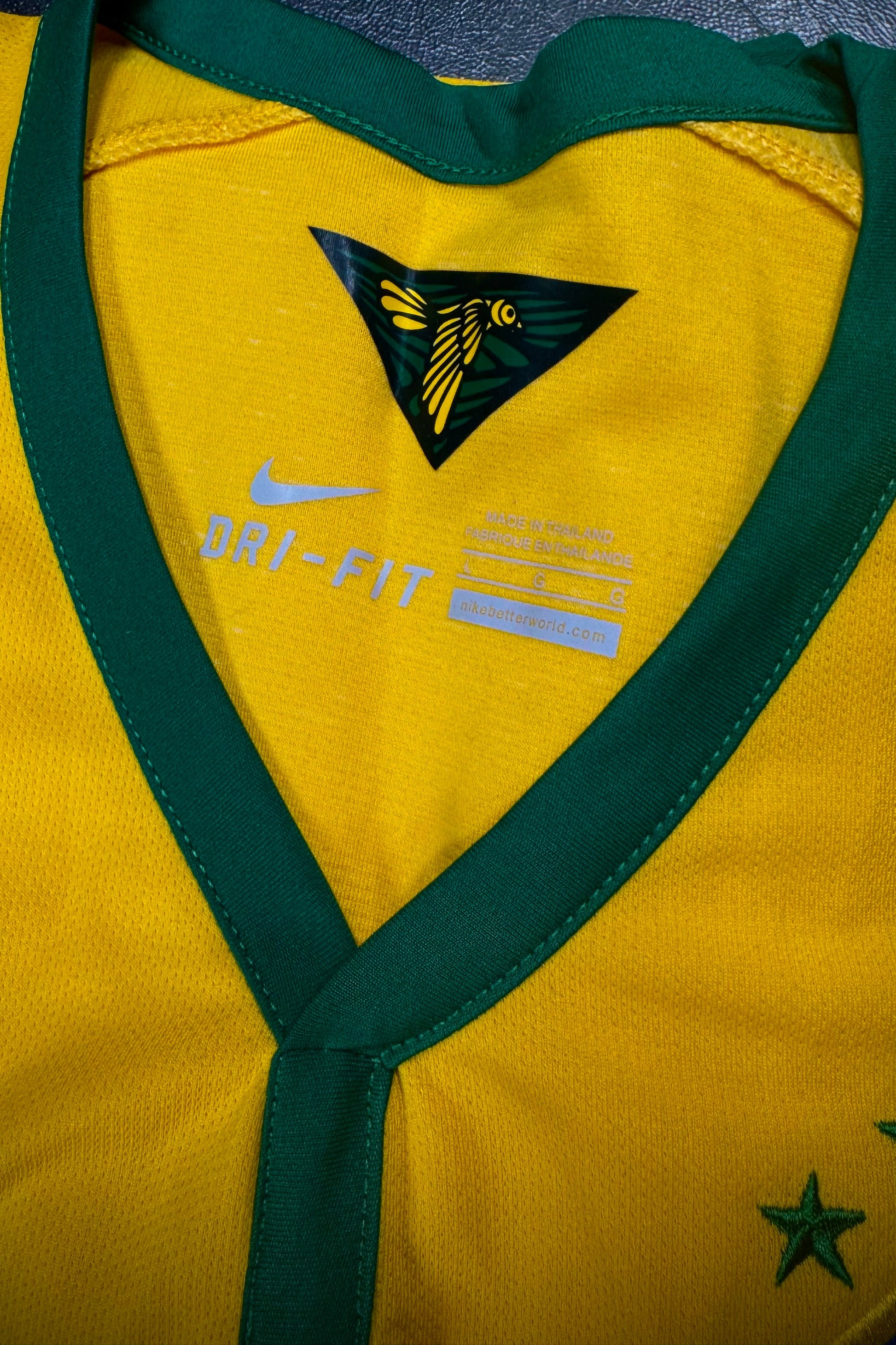 Yellow sports jersey with green accents and Nike logo on a dark surface