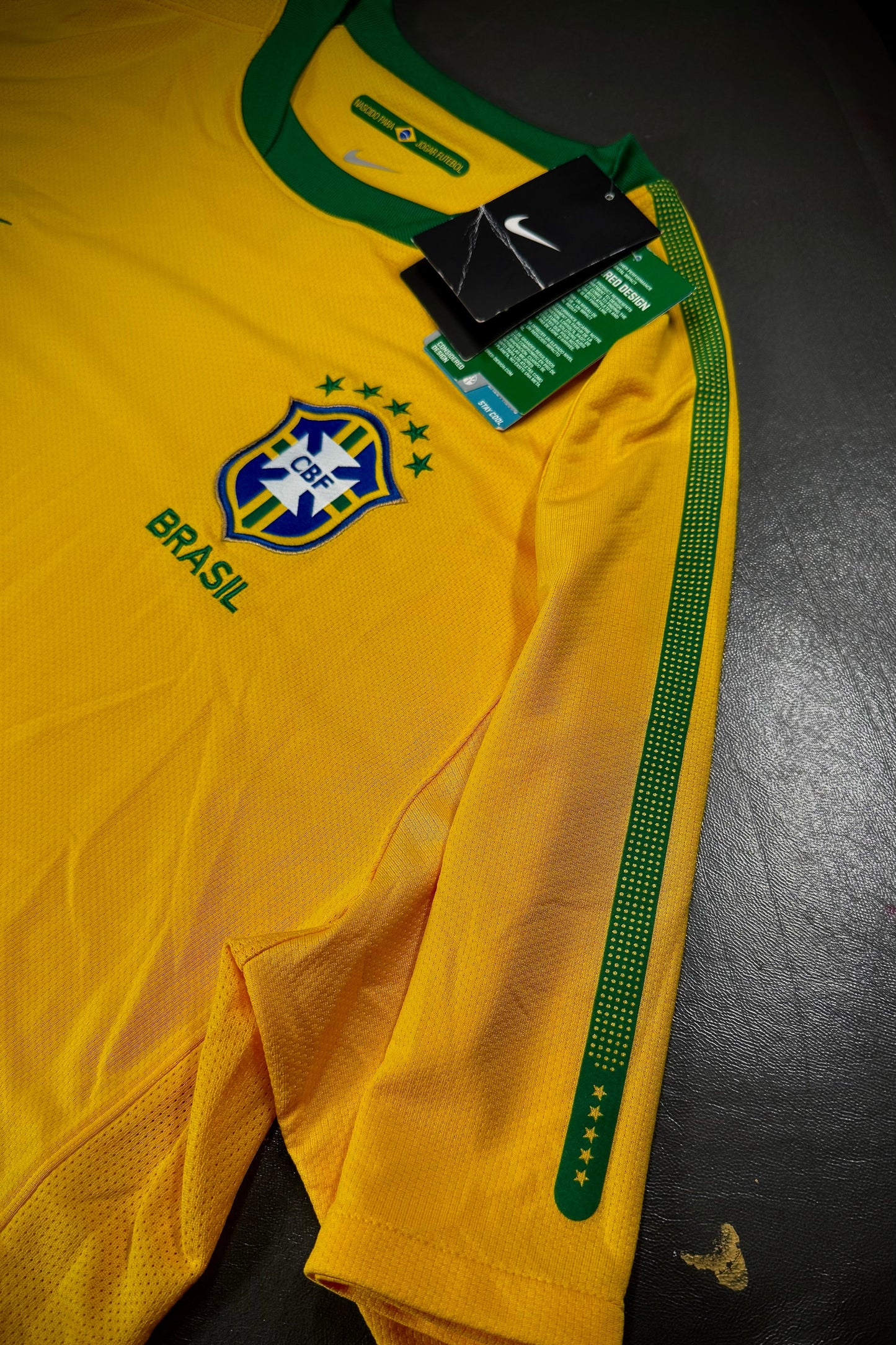 Yellow sports jersey with green accents and a visible brand tag on a dark surface