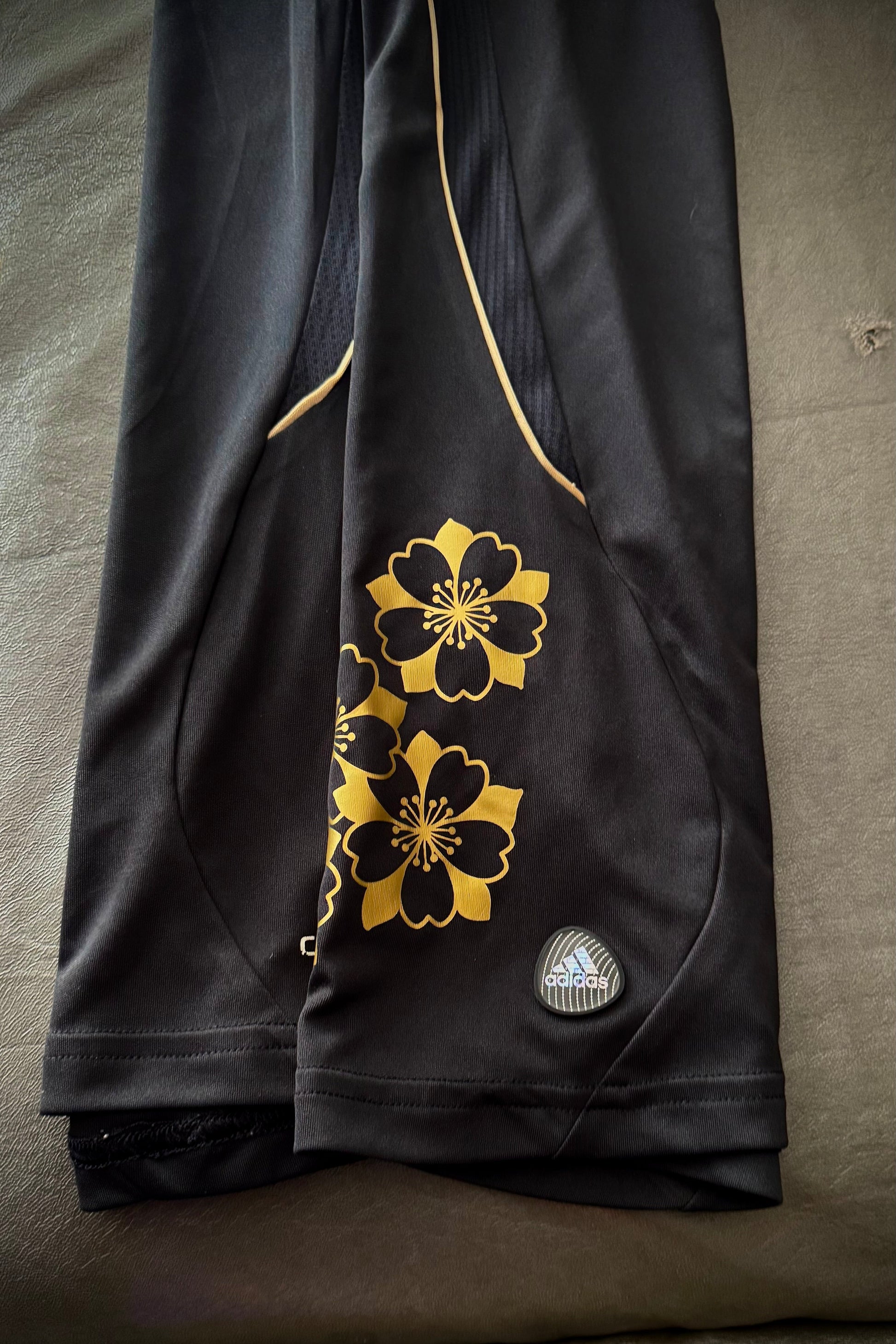 Black shorts with gold floral patterns on a gray surface