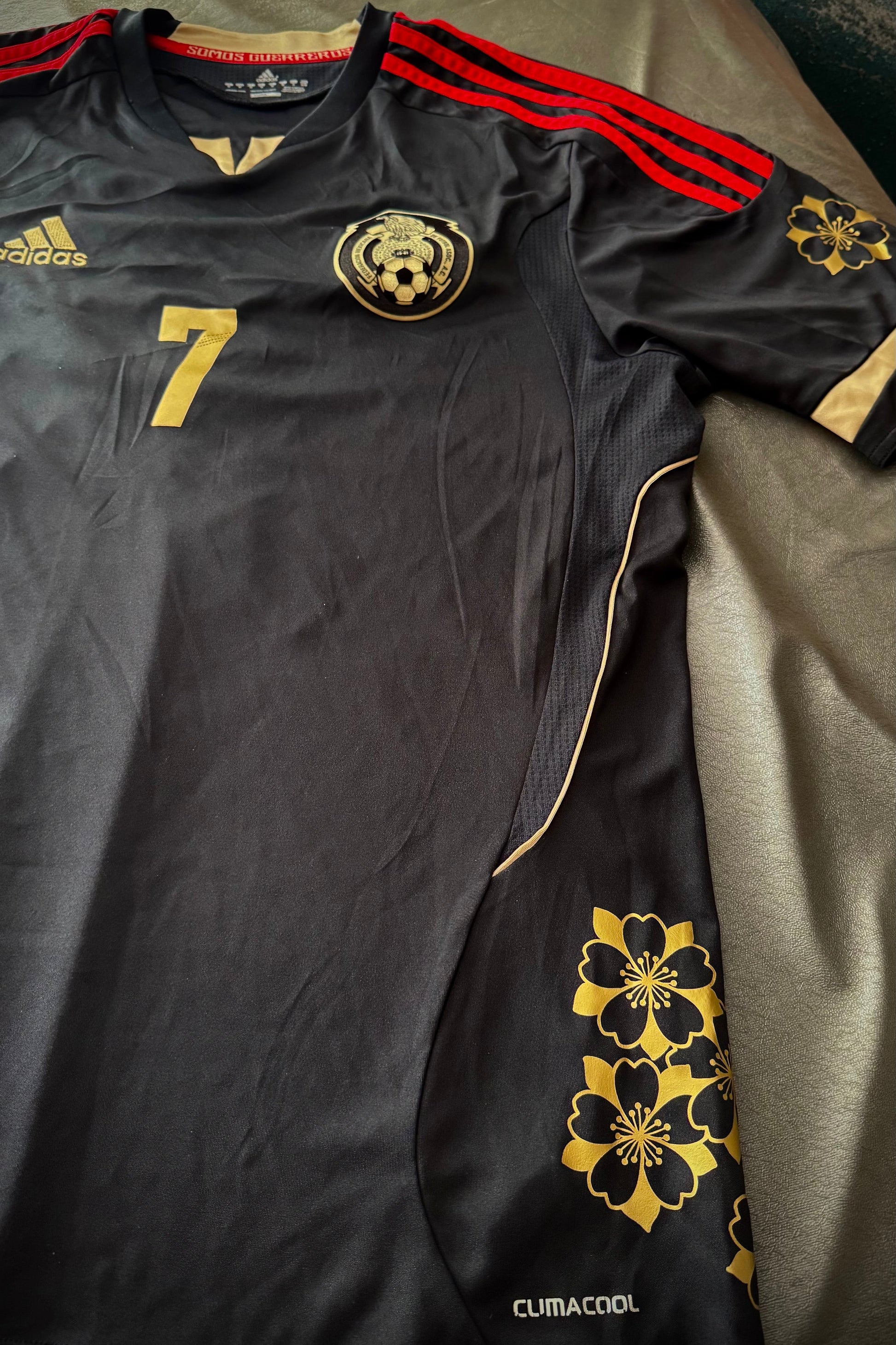 Black sports jersey with gold and red accents on a bed