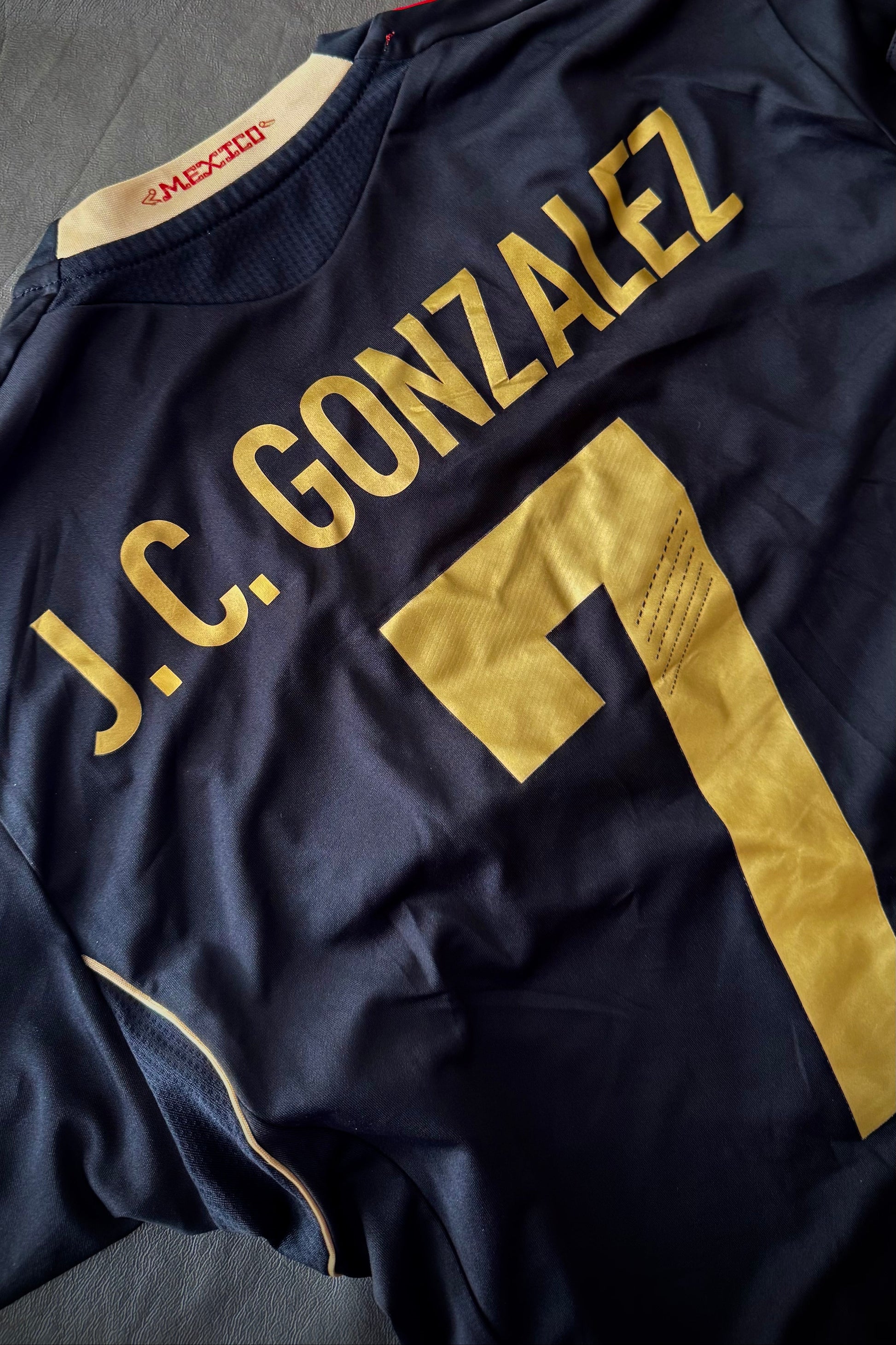 Navy sports jersey with 'J.C. Gonzalez' and number '7' in gold on a textured surface.
