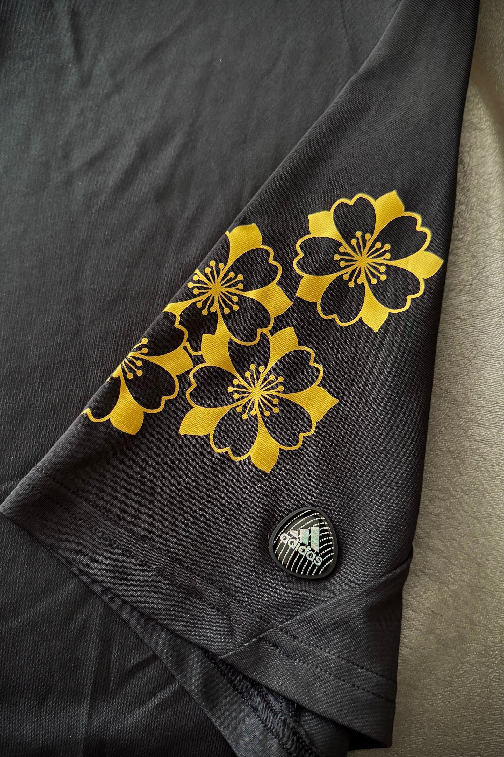 Dark fabric with yellow floral patterns and a small logo on a neutral background