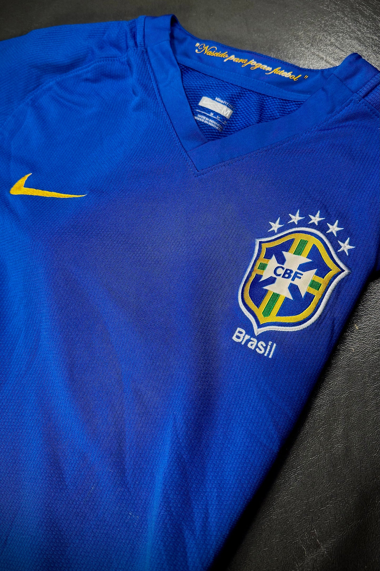Blue sports jersey with Nike logo and CBF Brasil emblem on a dark surface