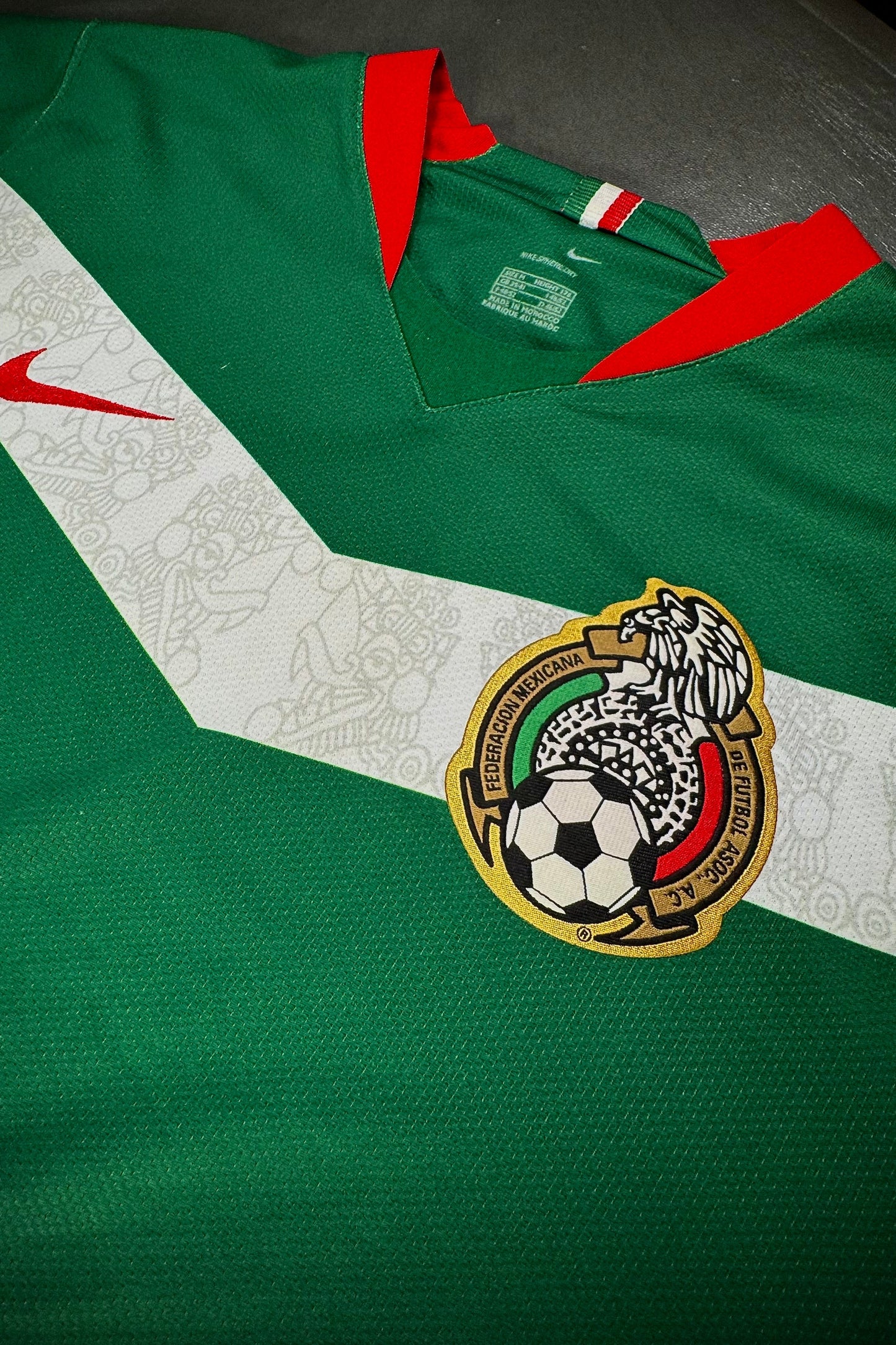 Green sports jersey with a logo featuring a soccer ball on a white background