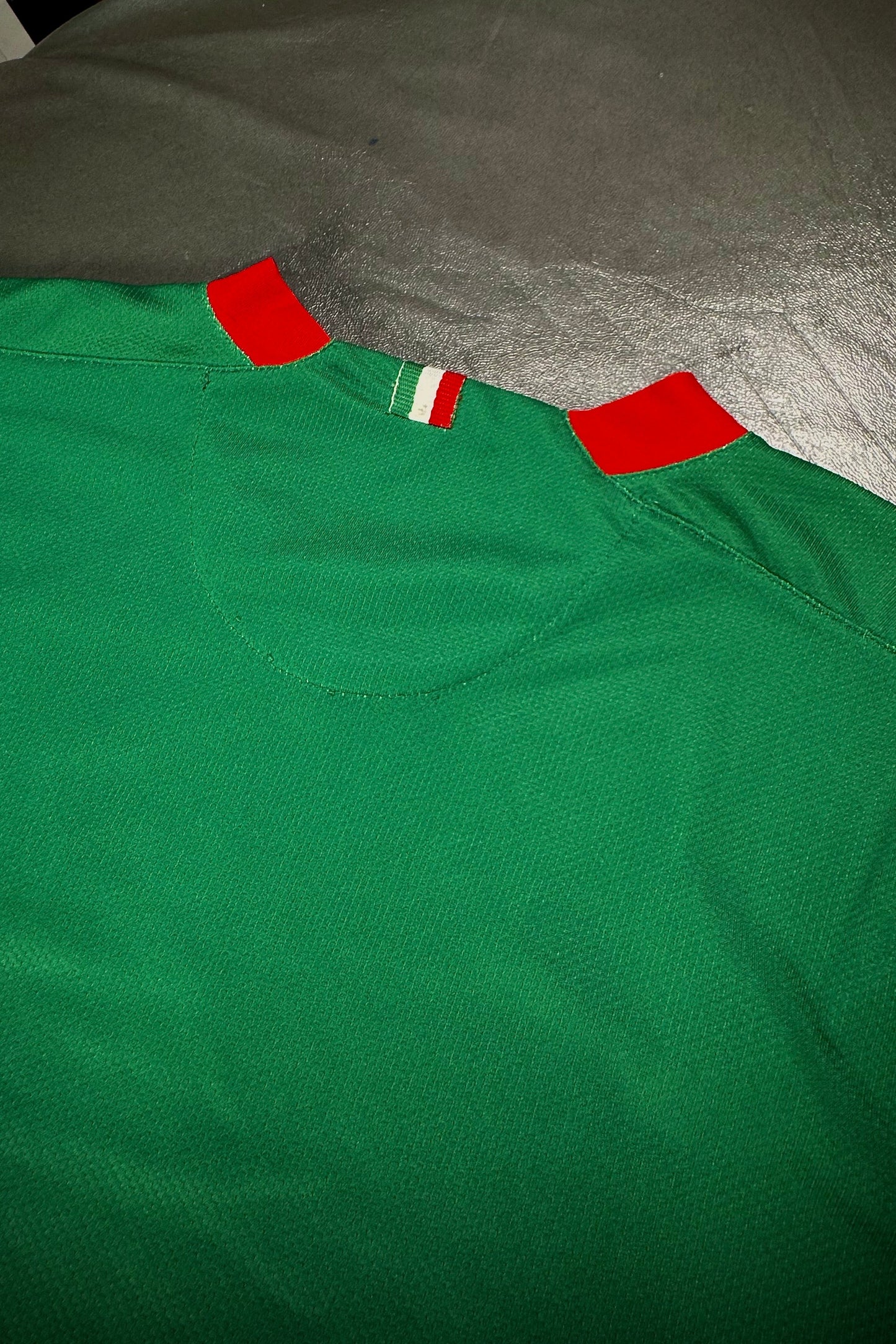 Green shirt with red accents on a gray surface