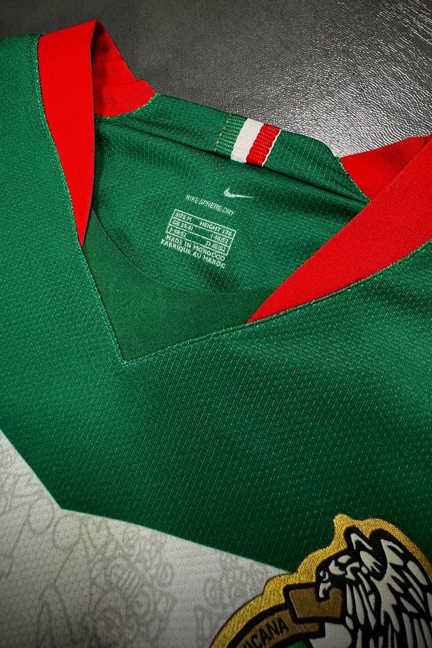 Green sports jersey with red collar on a dark surface