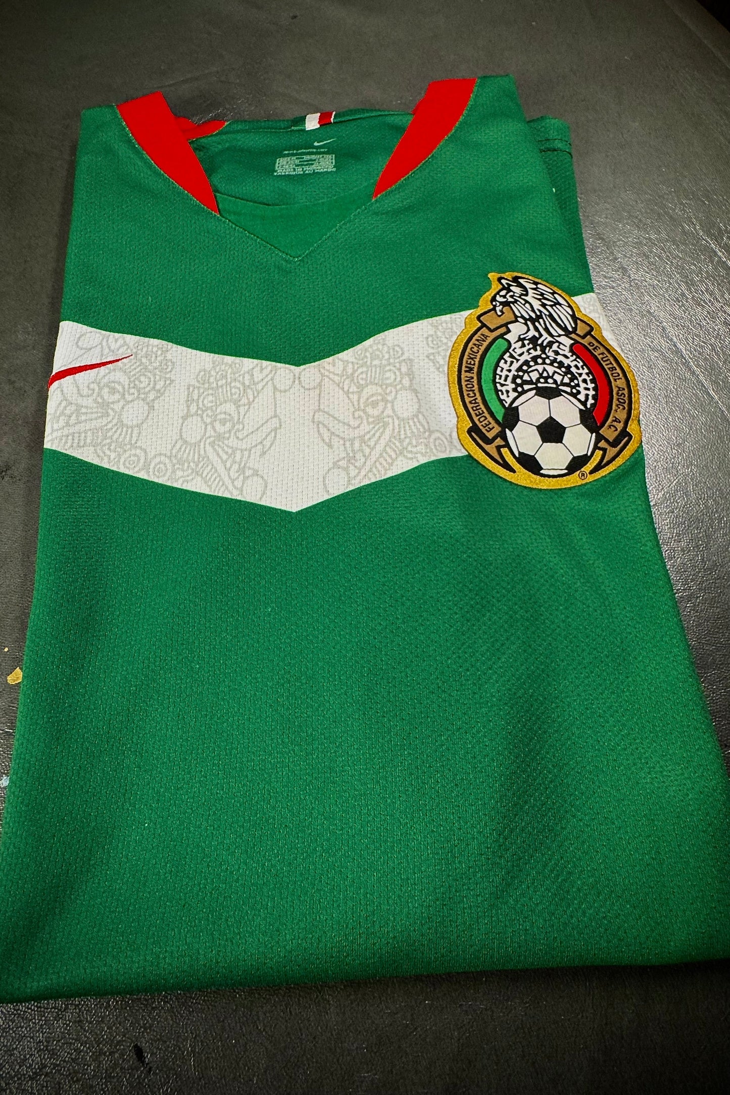 Green sports jersey with a logo on a dark surface