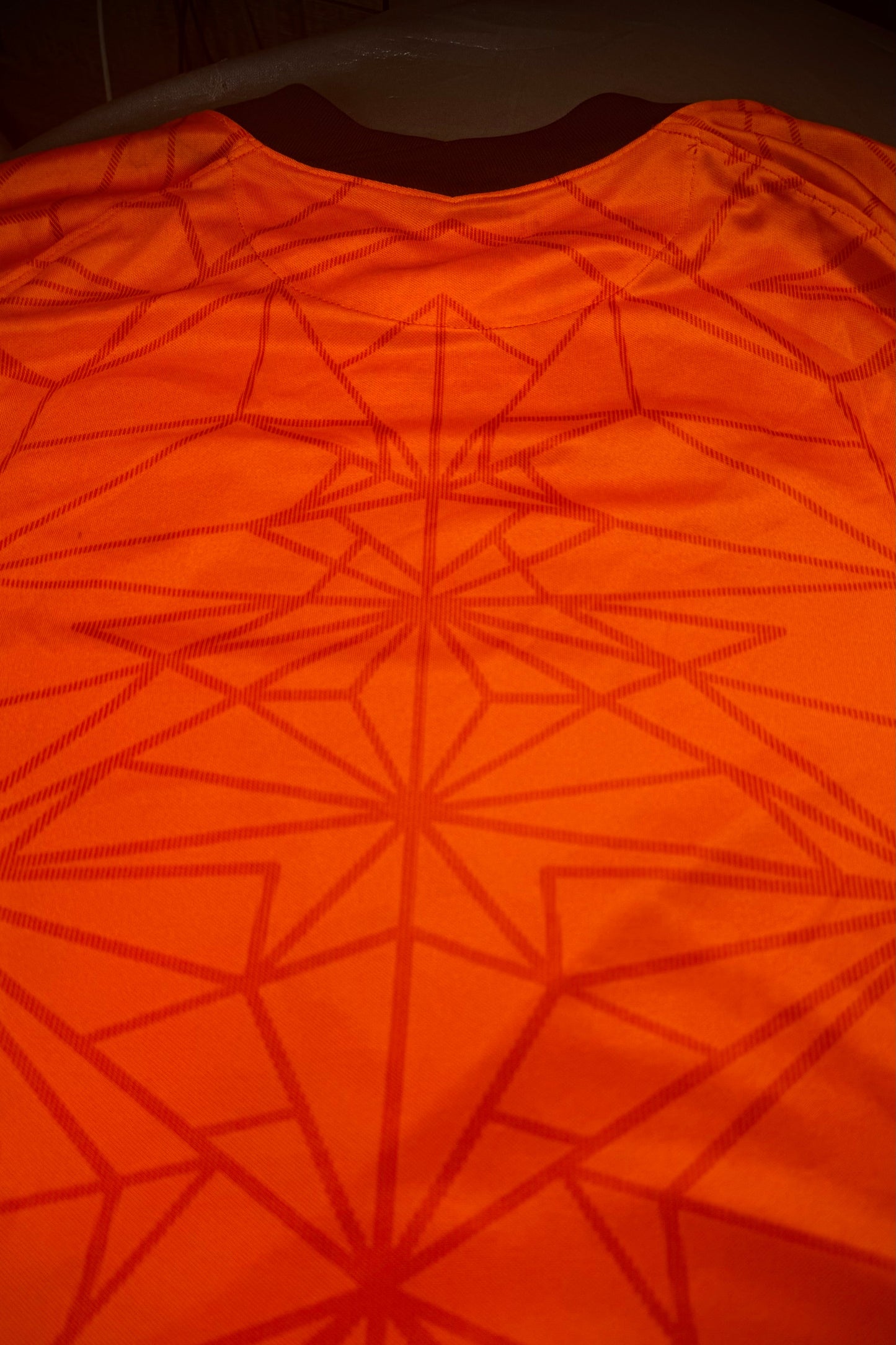 Geometric patterned fabric in orange with a dark background