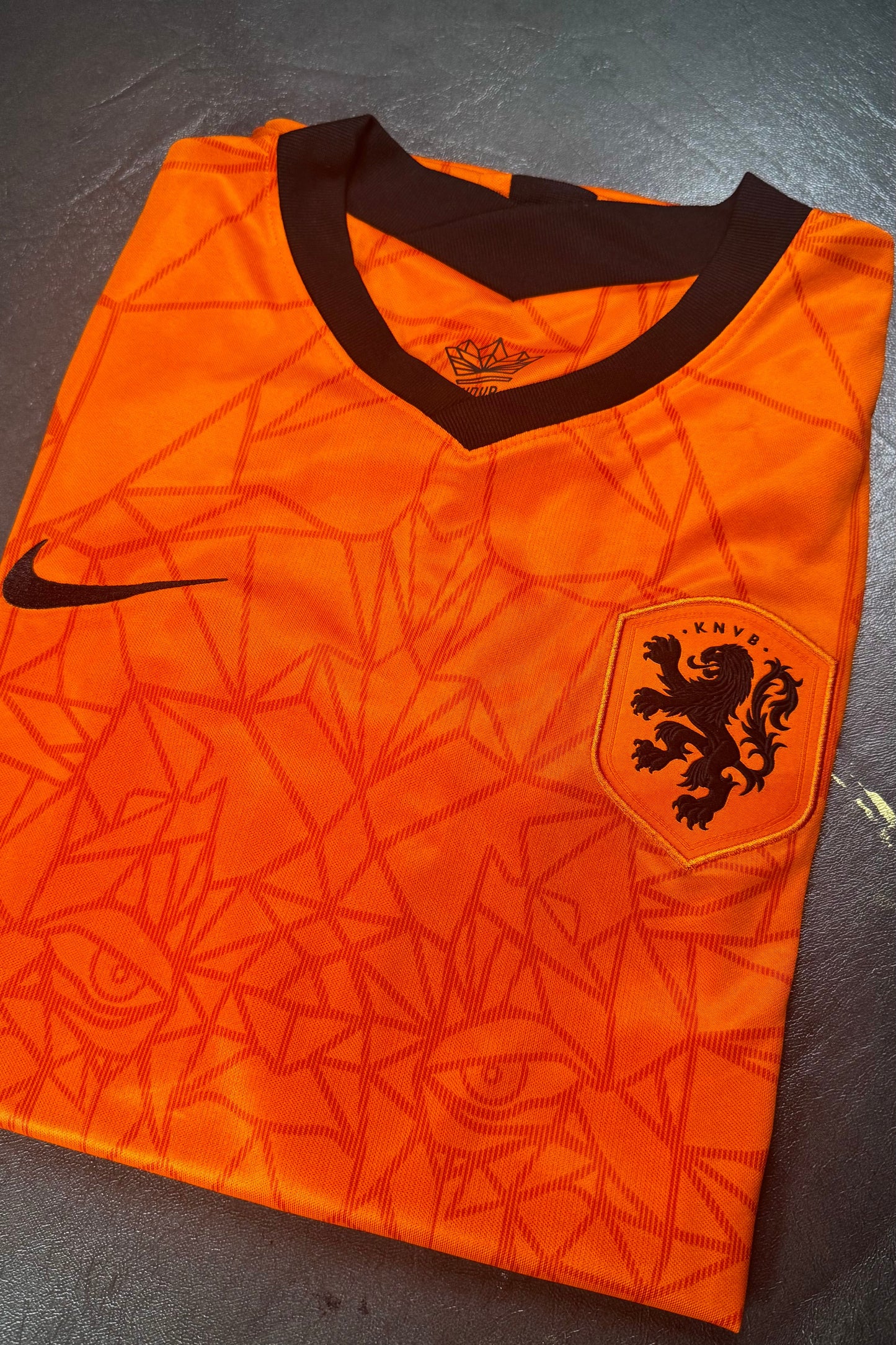 Orange sports jersey with a logo on a dark surface