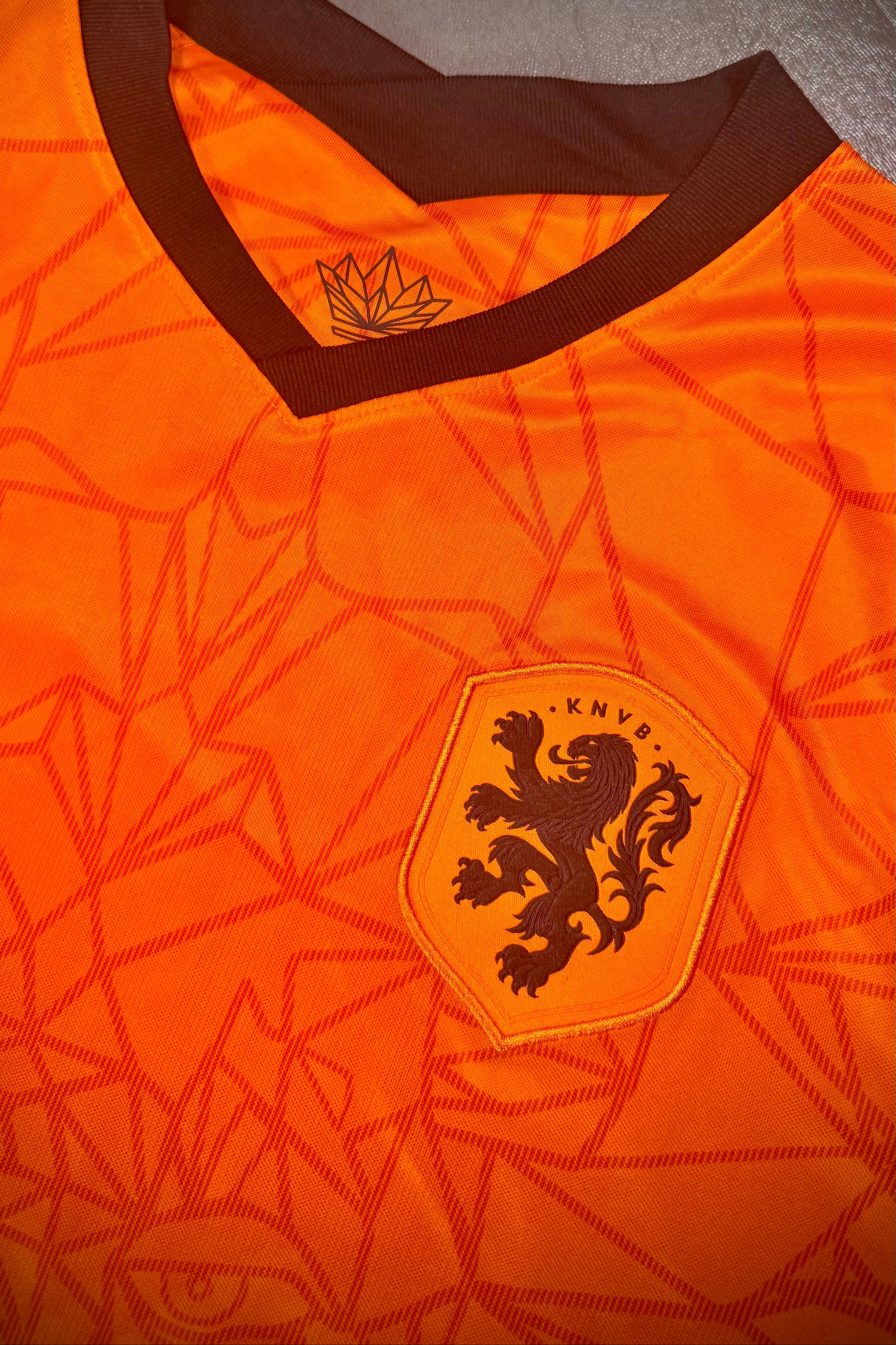 Orange sports jersey with a lion emblem on a gray surface