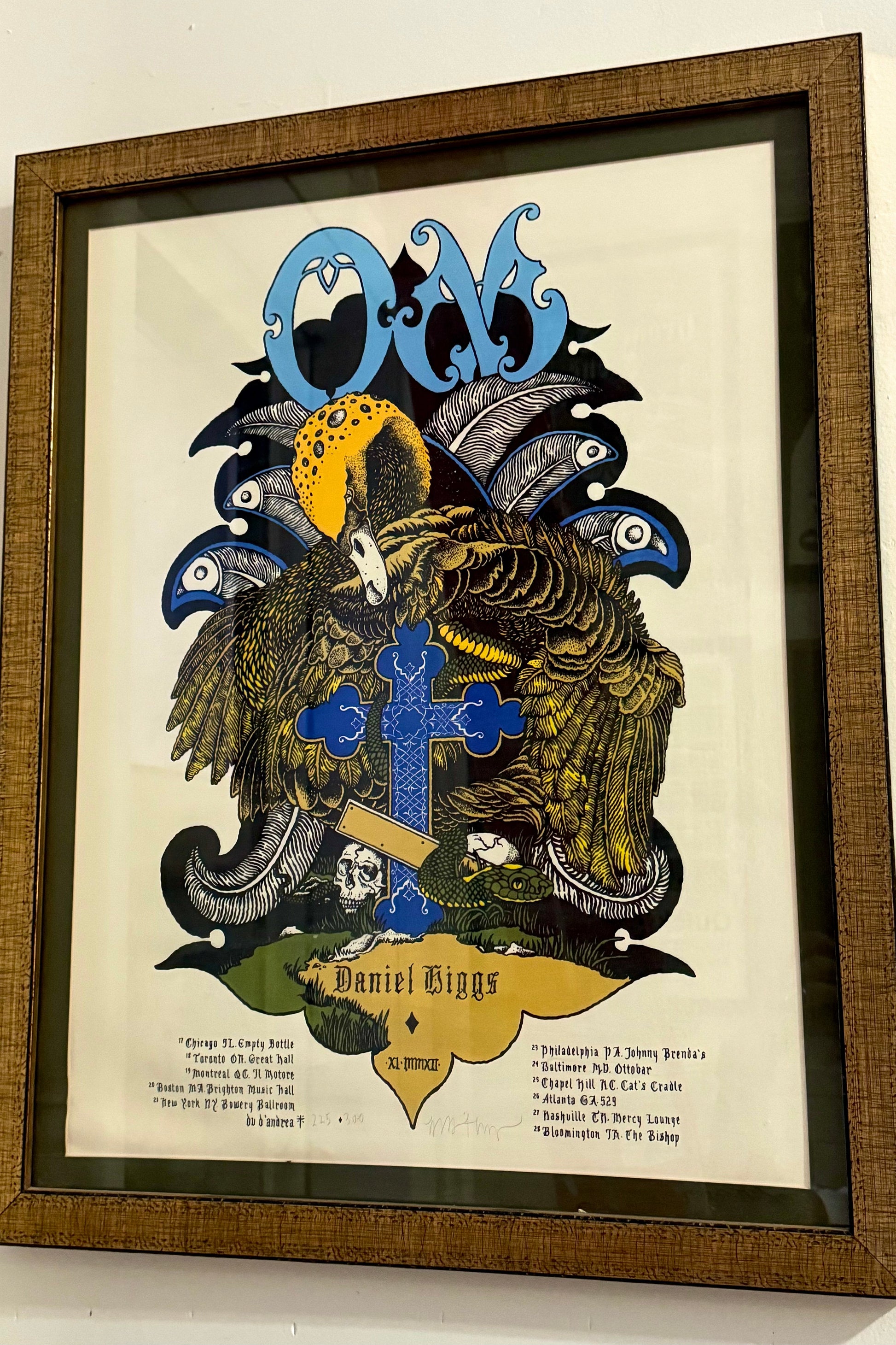 Framed screen print poster featuring the band 'OM' with a distinctive graphic design in multiple colors, signed and numbered edition of 300.