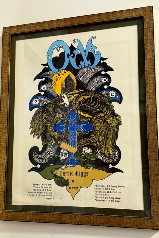 Framed screen print poster featuring the band 'OM' with a distinctive graphic design in multiple colors, signed and numbered edition of 300.