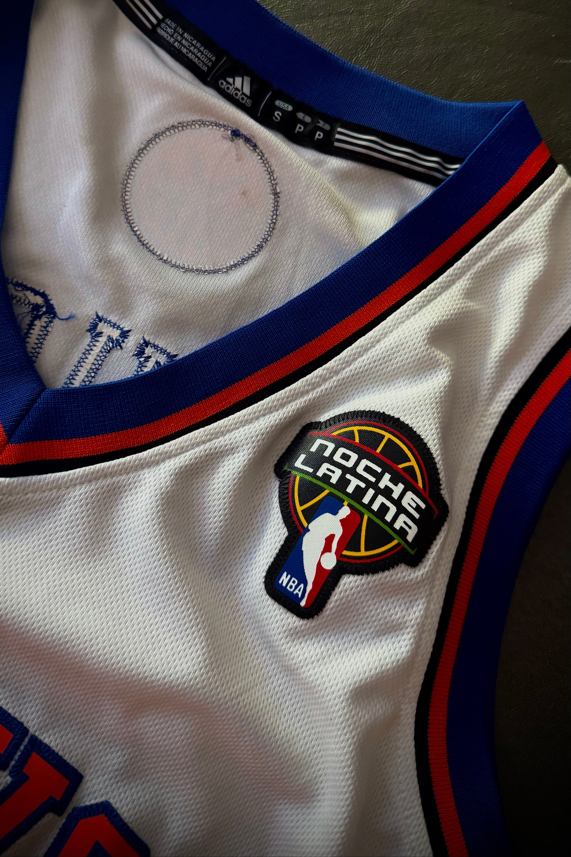Close-up of a sports jersey with a 'Noche Latina' patch and NBA logo.