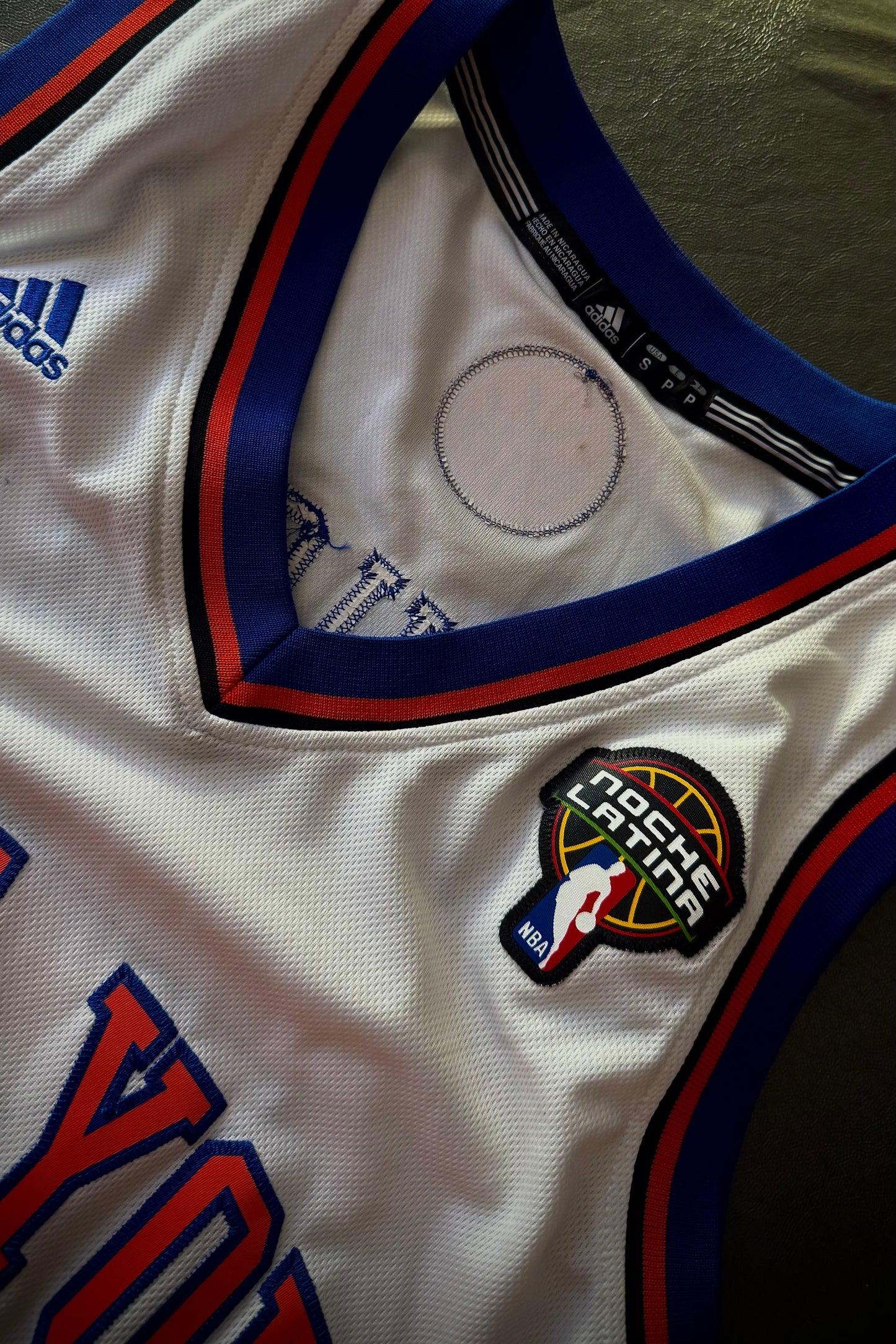Close-up of a sports jersey with Adidas logo and various patches.