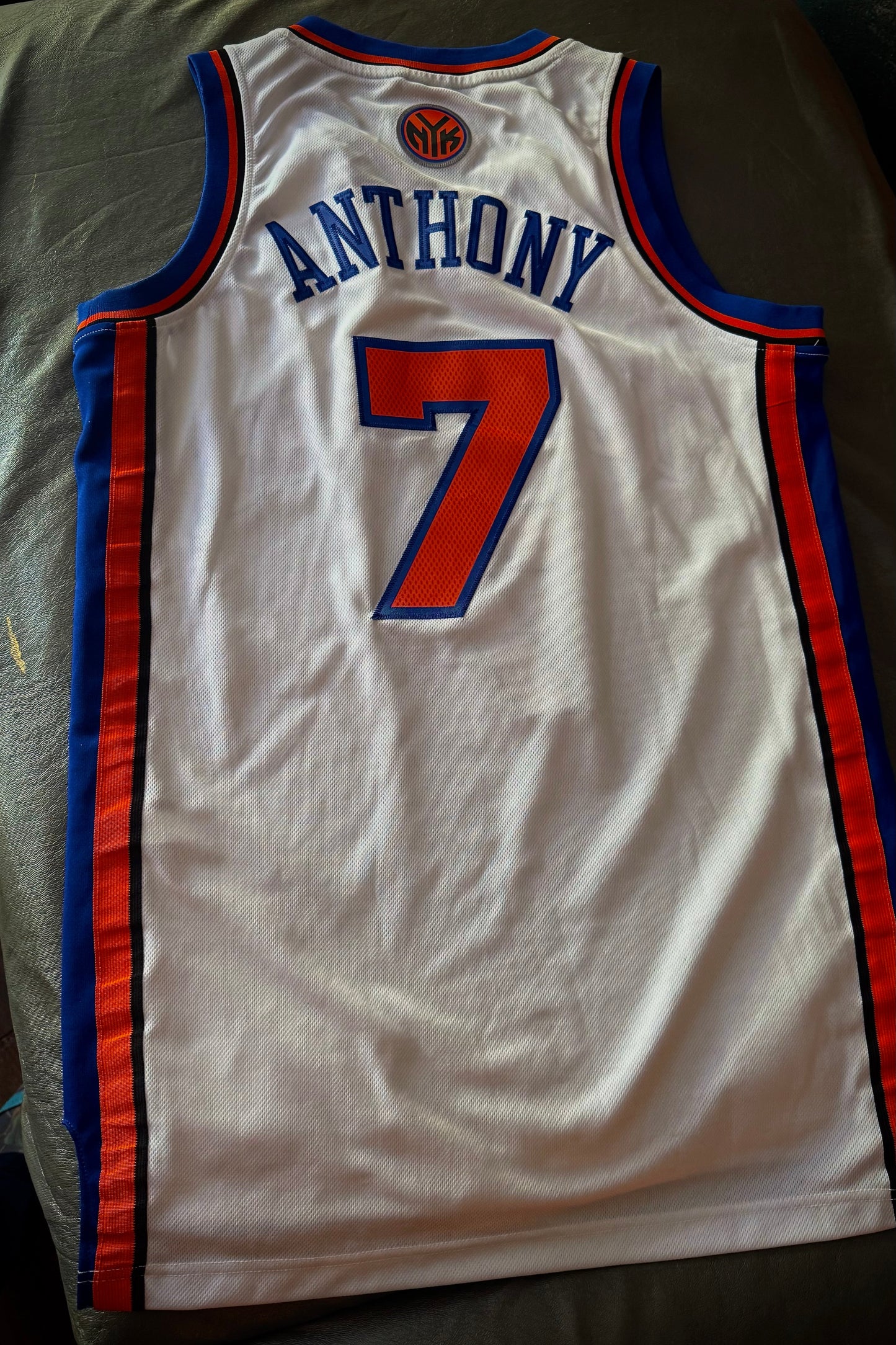 Basketball jersey with number 7 and name 'Anthony' on a bed