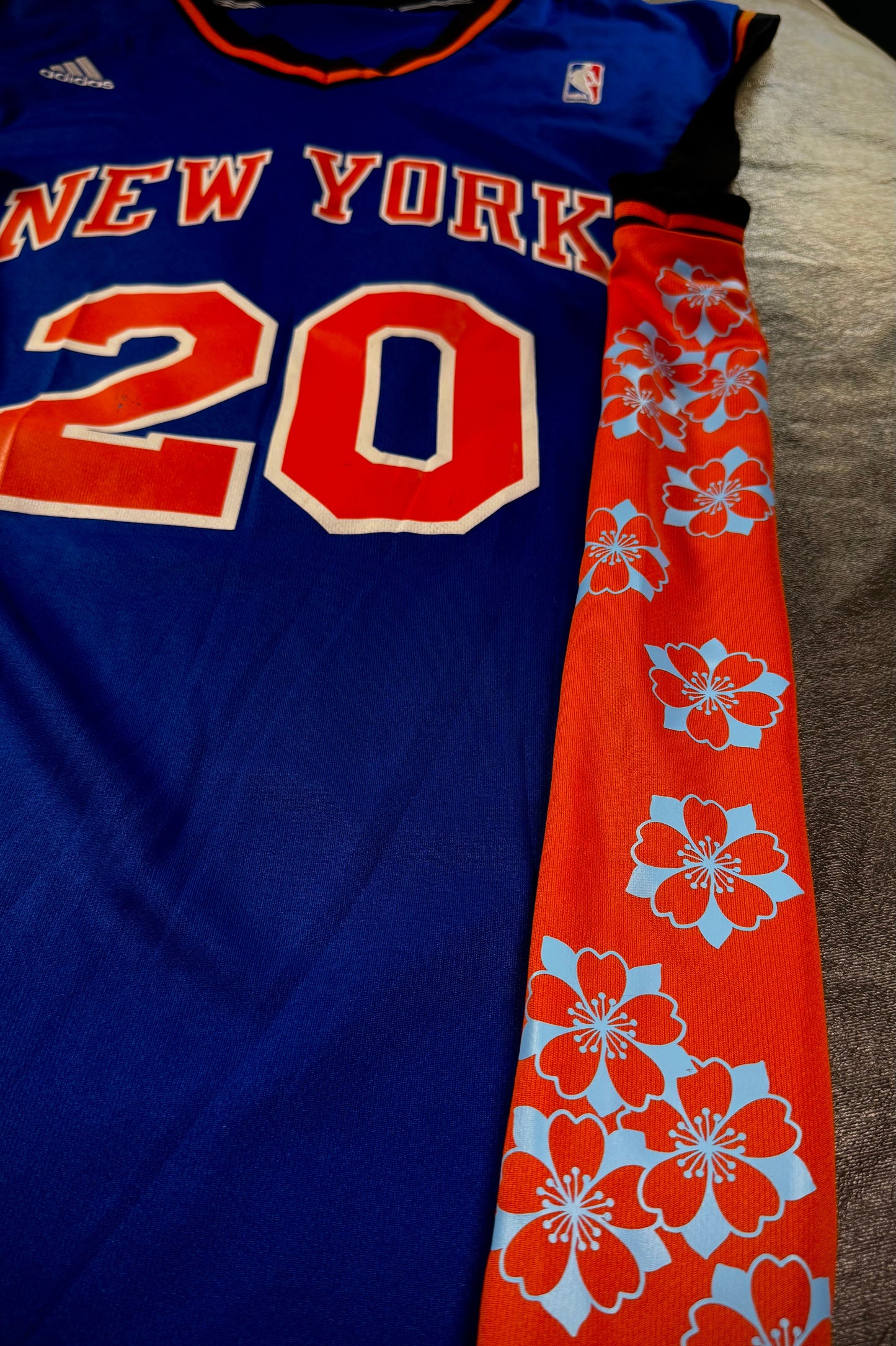 Blue sports jersey with 'New York' and number '20', paired with an orange floral-patterned tie.