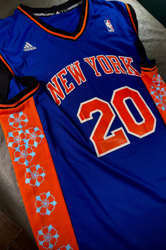 Blue sports jersey with 'New York' and number '20' on a bed