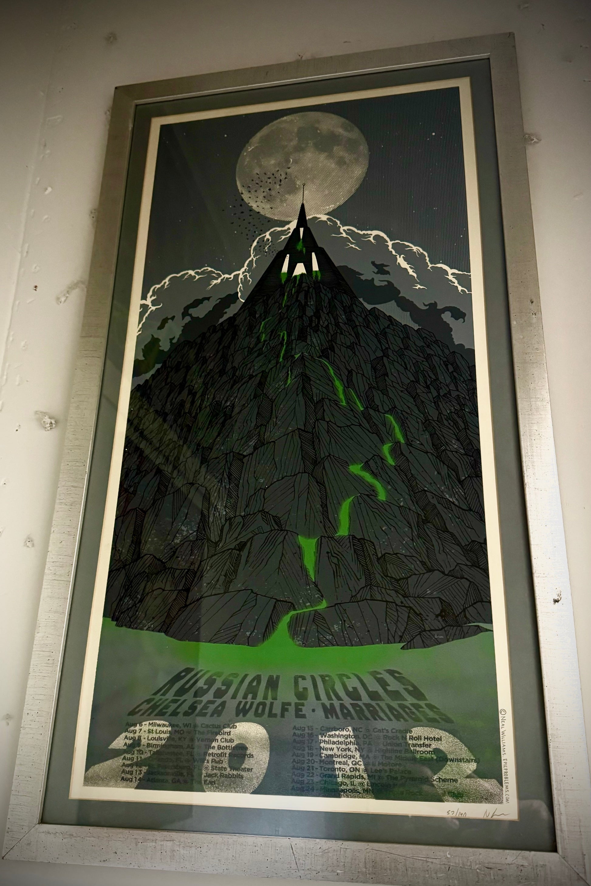 A framed poster featuring a black and green image with text, commemorating a 2012 concert by Russian Circles at the Highline Ballroom.