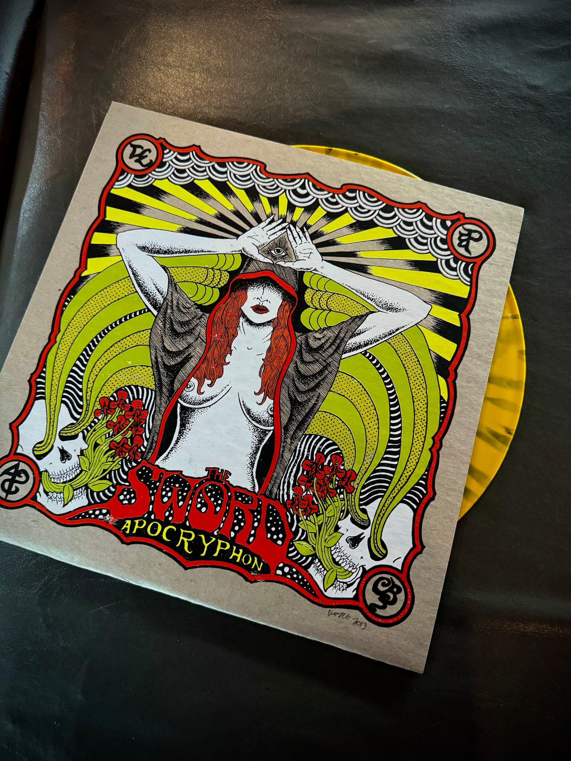 Vinyl record with a stylized cover featuring a woman and abstract designs on a dark surface.