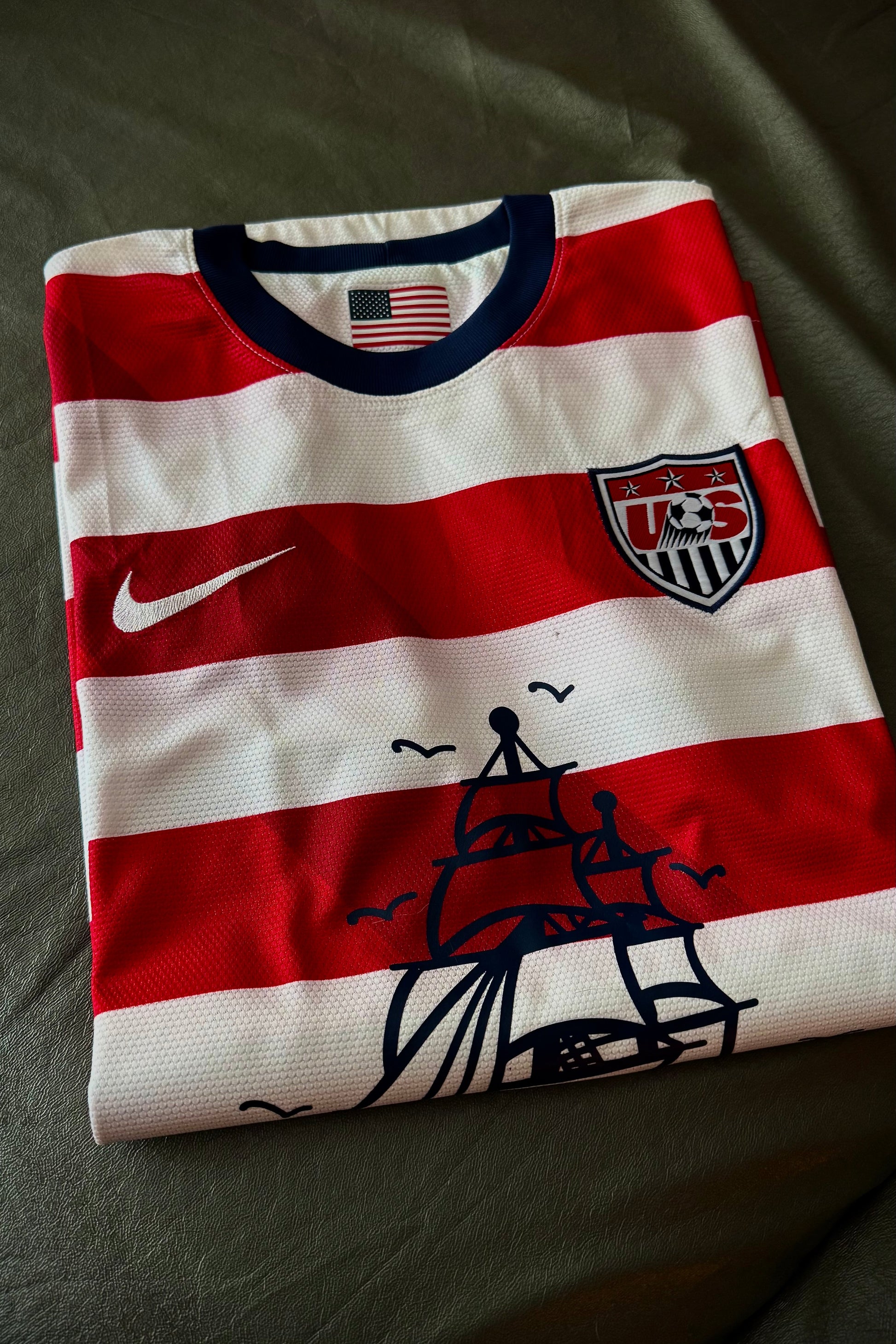 Folded red and white striped shirt with Nike logo and American flag design on a dark surface