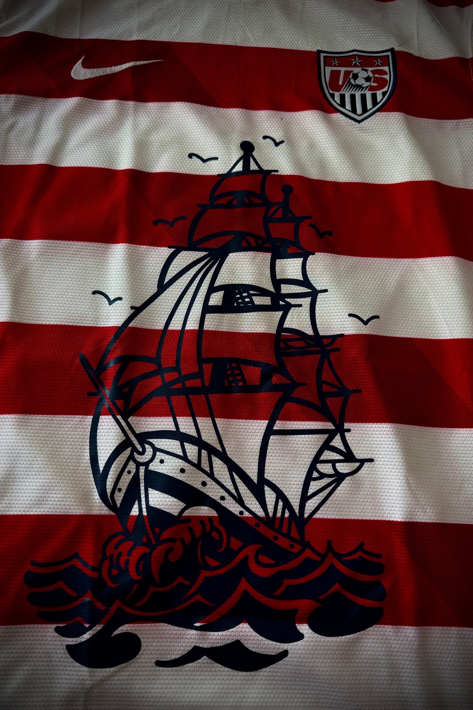 Red and white striped fabric with a black ship design and U.S. flag logo.