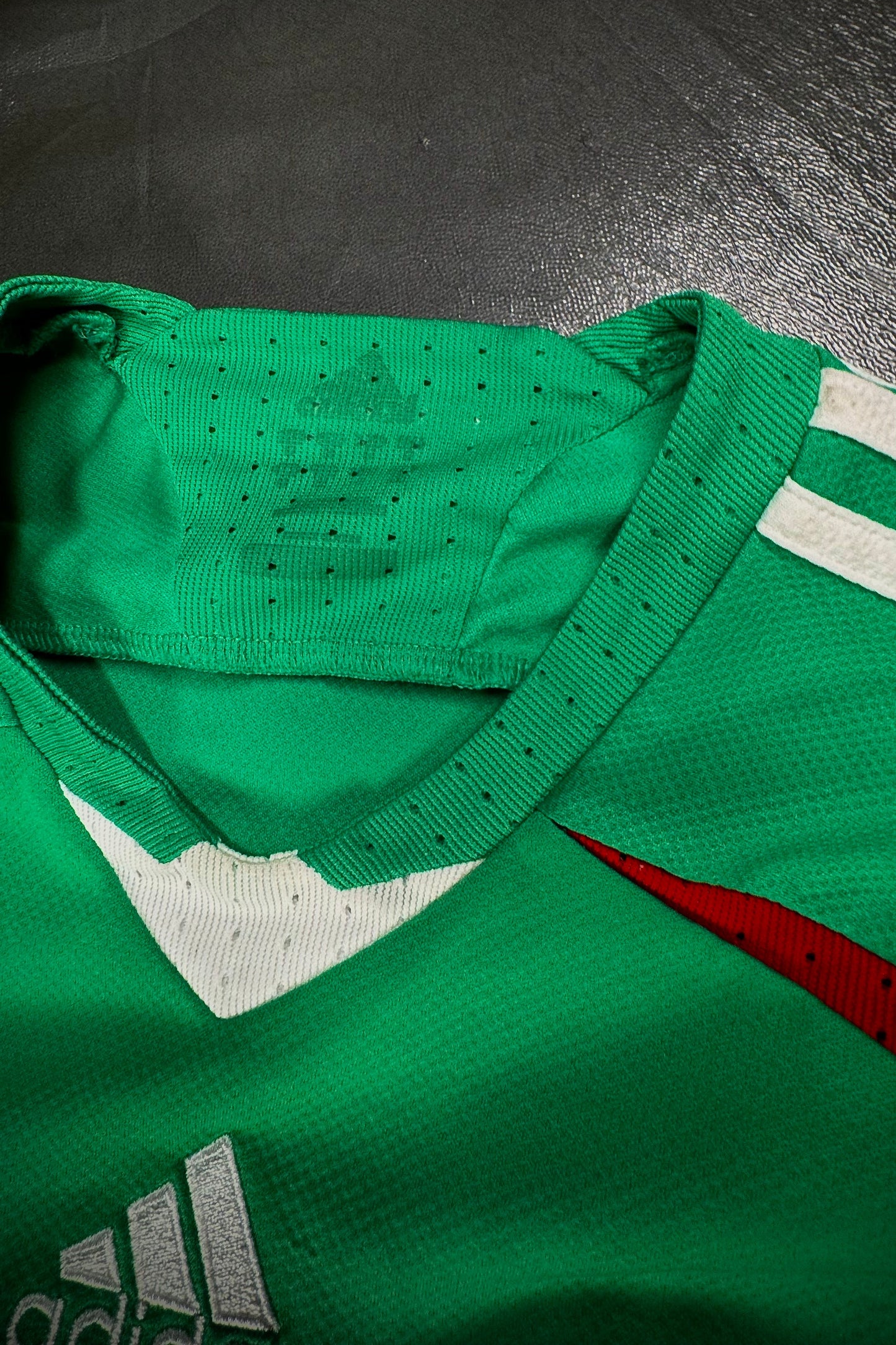 Green sports jersey with Adidas logo on a dark surface
