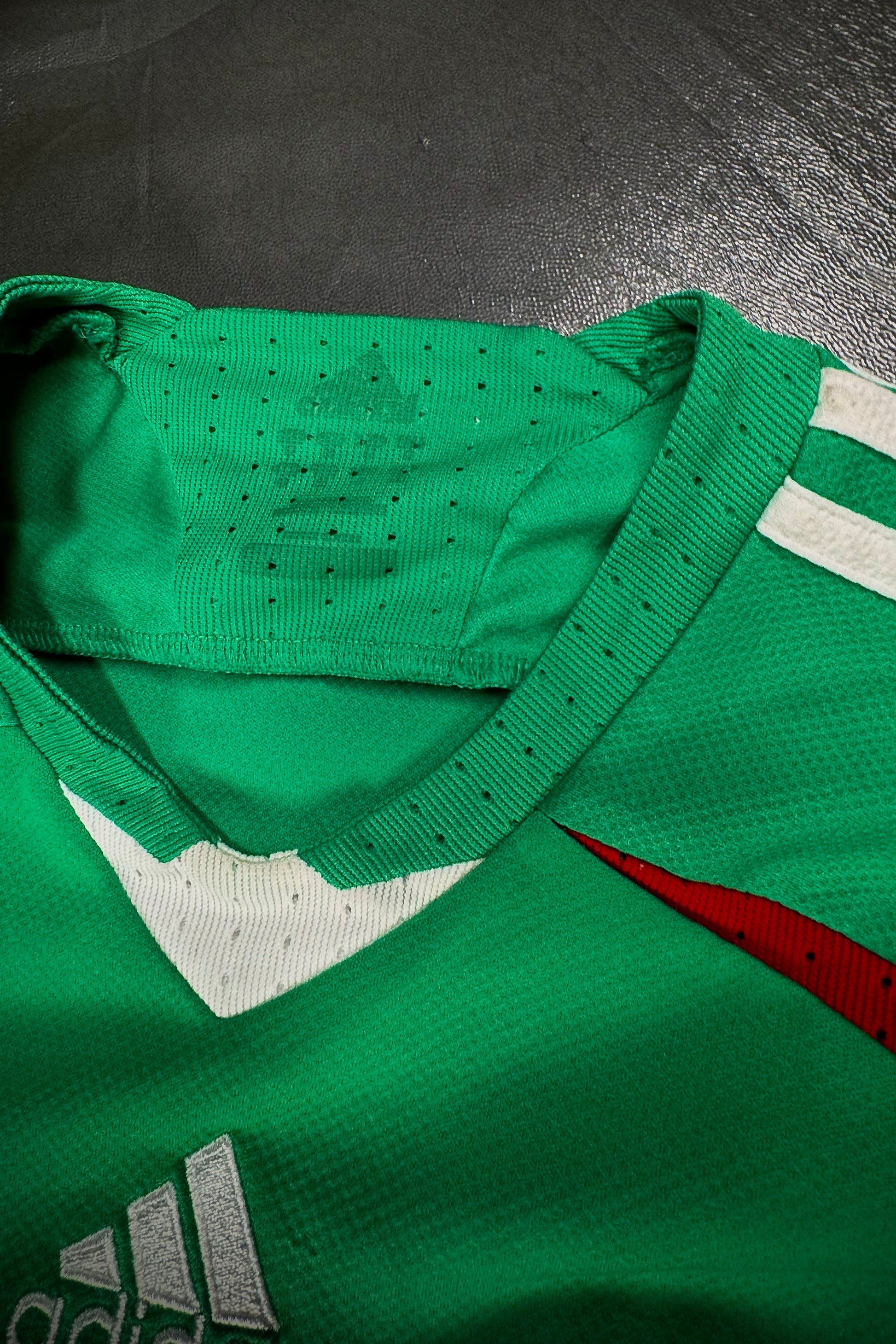 Green sports jersey with Adidas logo on a dark surface