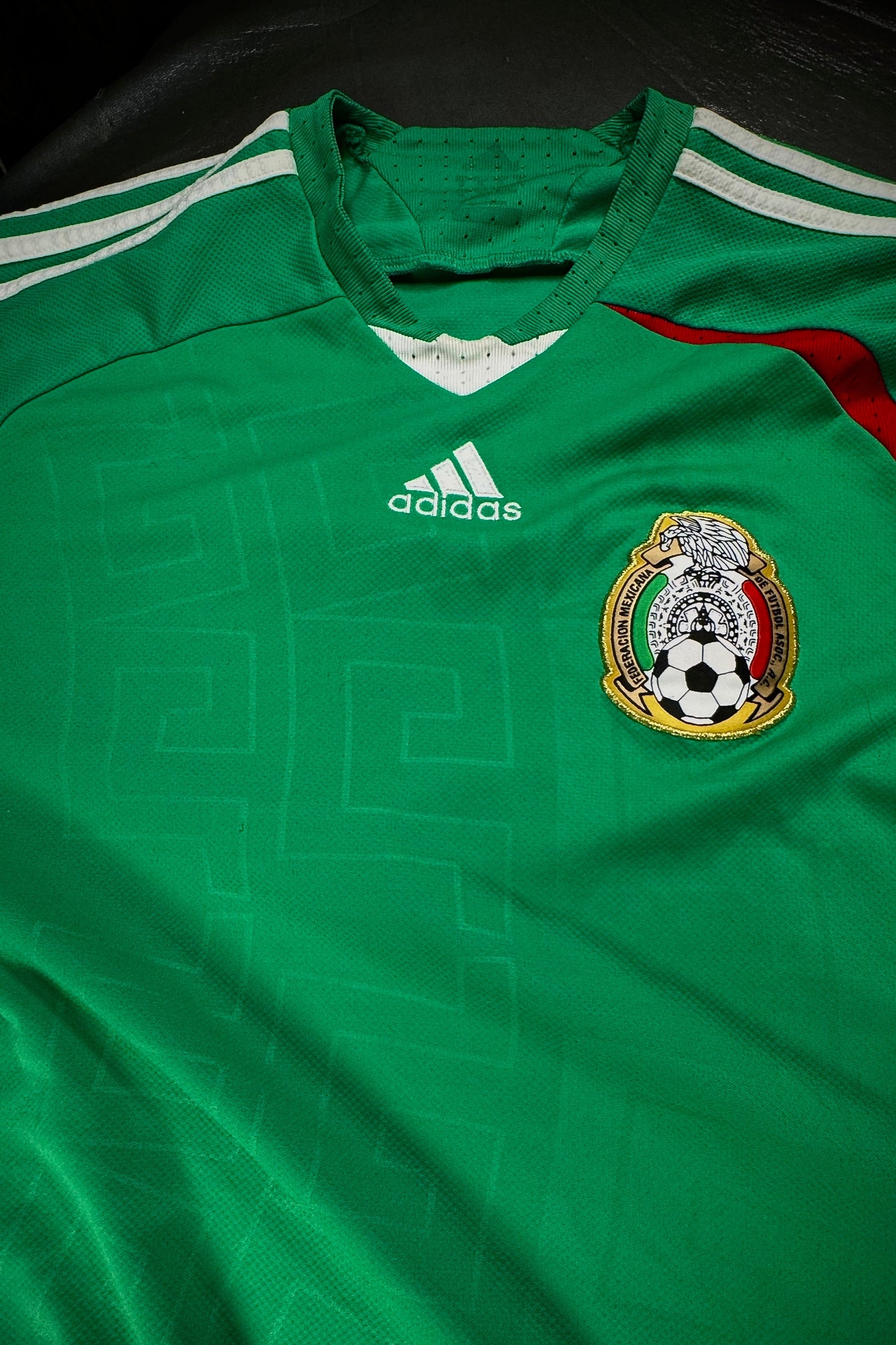Green soccer jersey with Adidas logo and Mexican emblem on a dark background